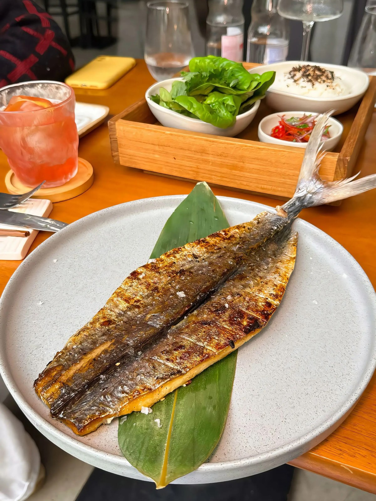 Peixe inteiro selado na parrilla, sobre folha de bananeira